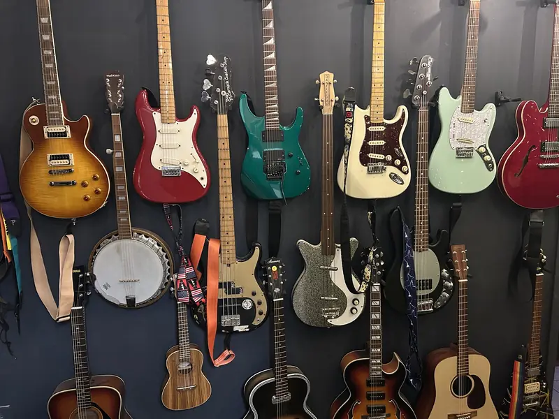 Wall of electric and acoustic guitars, a banjo and ukuleles