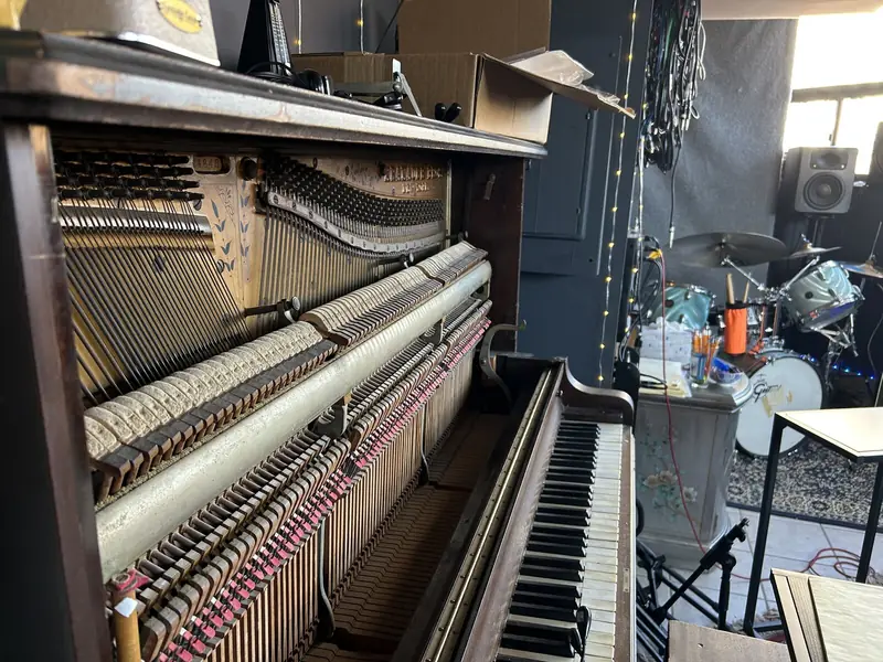 Vintage upright piano with the front open, in the live room